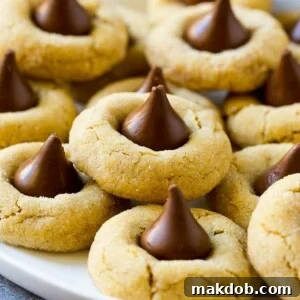 A beautifully arranged plate featuring a stack of classic peanut butter blossoms, each adorned with a chocolate kiss, highlighting a timeless and beloved cookie recipe.