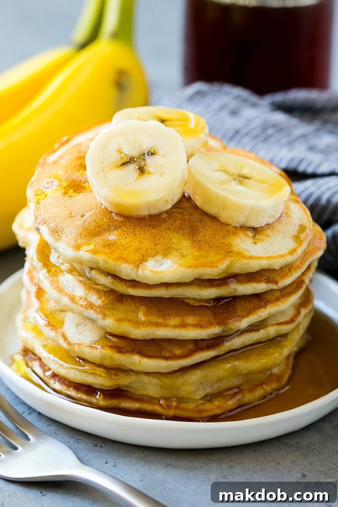 Fluffy Banana Pancakes with Maple Syrup A stack of golden-brown banana pancakes with banana slices and a generous drizzle of maple syrup, ready to be served.