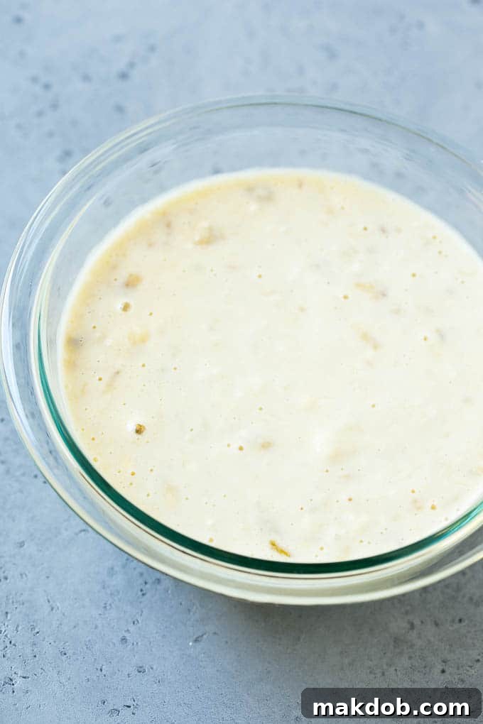 Homemade Banana Pancake Batter A bowl of freshly prepared banana pancake batter, showcasing its thick, creamy texture with visible specks of mashed banana.