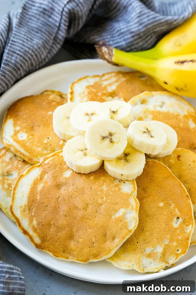 Banana Pancakes with Fresh Banana Topping A plate featuring a stack of banana pancakes generously topped with fresh banana slices, ready for a delicious breakfast.