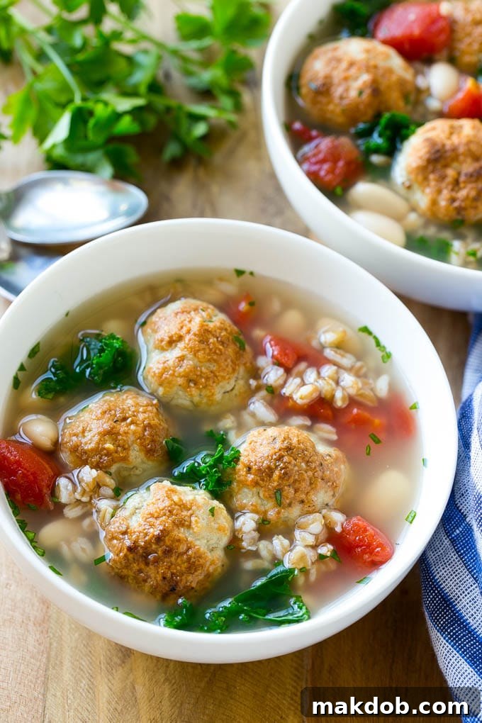 Two enticing bowls of farro soup, garnished with vibrant tomatoes, tender meatballs, and fresh kale, ready to be enjoyed.