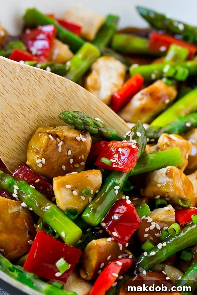 Chicken teriyaki stir fry simmering in a pan with a spatula, glistening with rich teriyaki sauce.