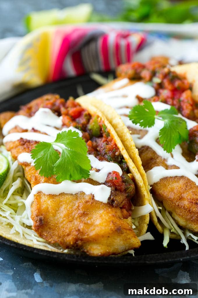 Baja fish tacos filled with fried fish, shredded cabbage, salsa and a creamy sauce, ready to be enjoyed.