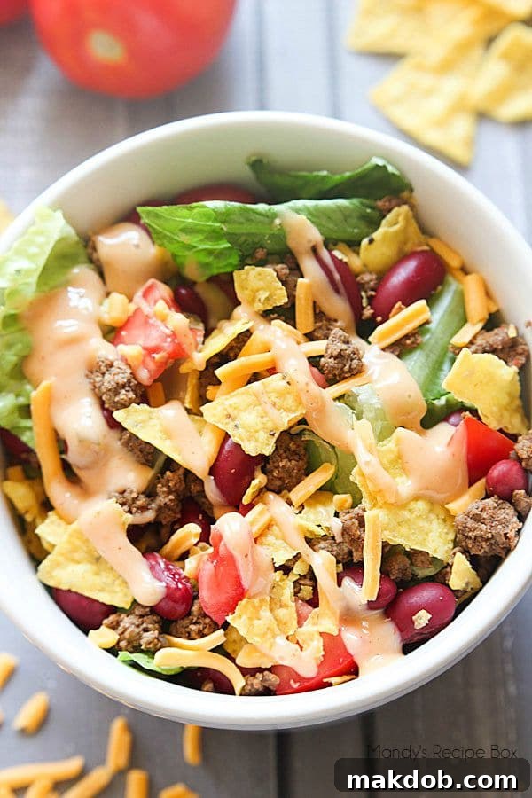 Hearty Taco Salad with ground meat, fresh lettuce, tomatoes, cheese, and sour cream in a large bowl.