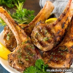 Grilled lamb chops on a plate garnished with parsley and lemon.