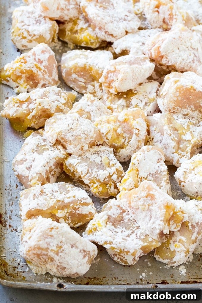 Sesame Chicken Recipe | Crispy Chicken | Asian Chicken #sesame #chicken #asian #dinner #dinneratthezoo Coated chicken breast pieces on a sheet pan, ready to be fried, showing the even white coating.