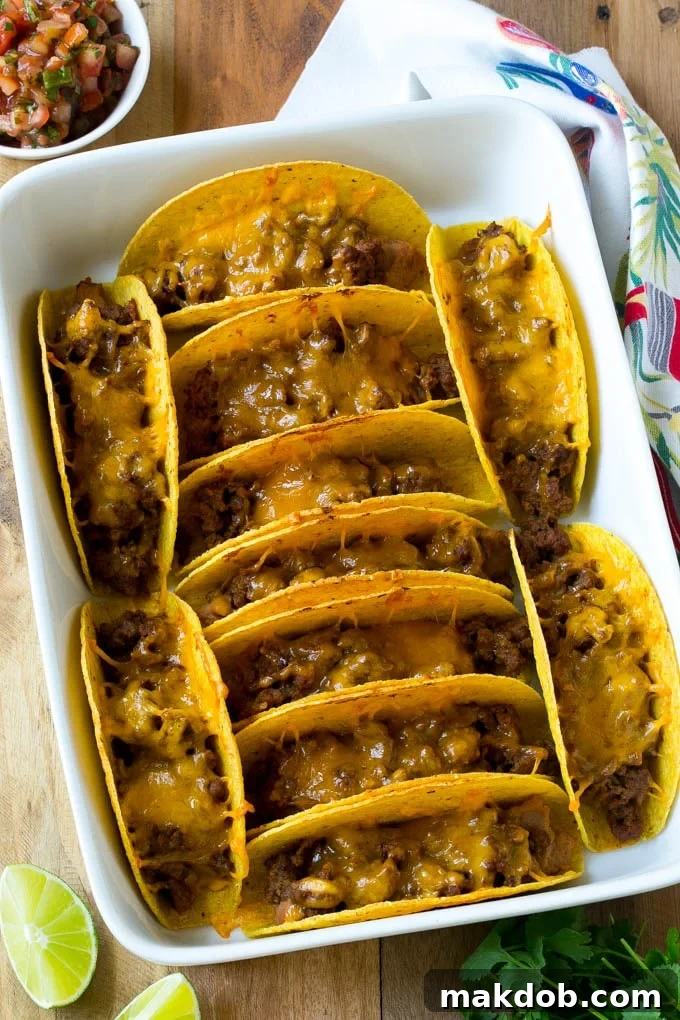 Baked beef tacos topped with melted cheese in a casserole dish.