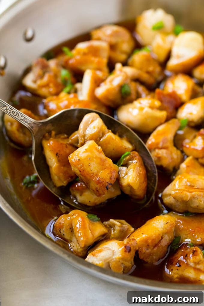 A pan of bourbon chicken with a serving spoon in it.