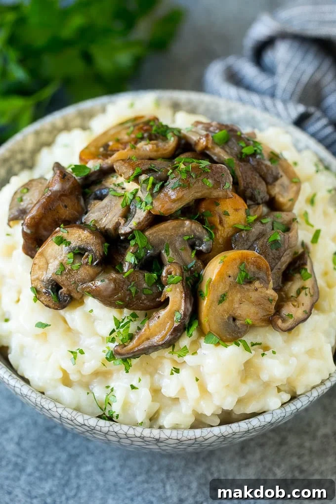 A bowl of mushroom risotto topped with garlic butter mushrooms.