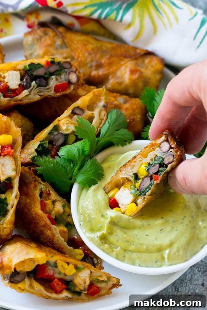 Best Southwestern Egg Rolls Recipe A crispy Southwestern chicken egg roll being dipped into a vibrant, creamy avocado ranch sauce, highlighting the rich flavors and textures.