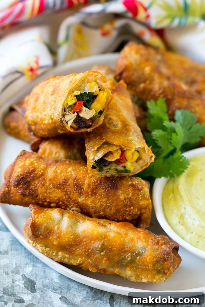 Crispy Southwestern Egg Rolls with Chicken Delicious Southwestern chicken egg rolls with bell peppers, black beans, and melted cheese, arranged on a serving plate ready for dipping.