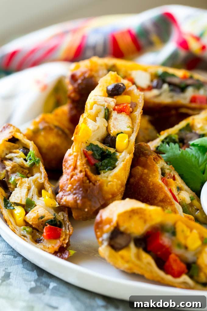 Delicious Southwest Egg Rolls Recipe Colorful chicken egg rolls, halved and served with a side of creamy avocado ranch sauce, showcasing the delicious filling.