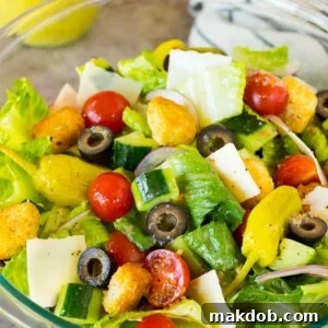 A bowl of Italian salad with cucumber, cheese and croutons.