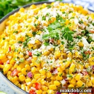 A bowl of Mexican corn salad topped with cheese and cilantro.
