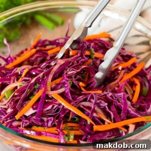 Tongs serving up a portion of red cabbage slaw.
