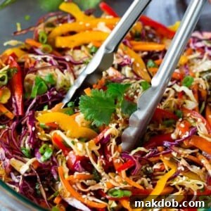 Tongs serving up a portion of Asian slaw.