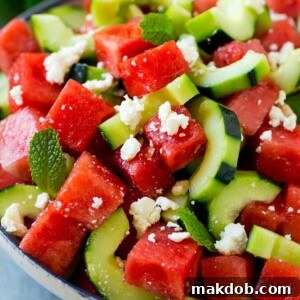 Watermelon salad with cucumbers, feta cheese and mint in a serving bowl.