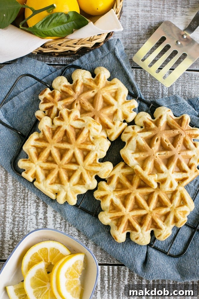 Close-up of a stack of lemon sour cream waffles, garnished with lemon slices and berries, ready to be enjoyed.