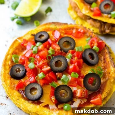 A Mexican pizza topped with cheese, tomatoes and olives.
