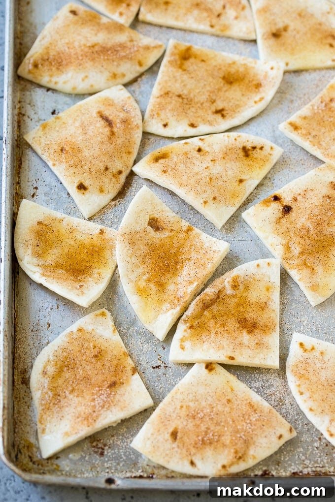 Tortilla wedges coated in cinnamon sugar on a baking sheet.