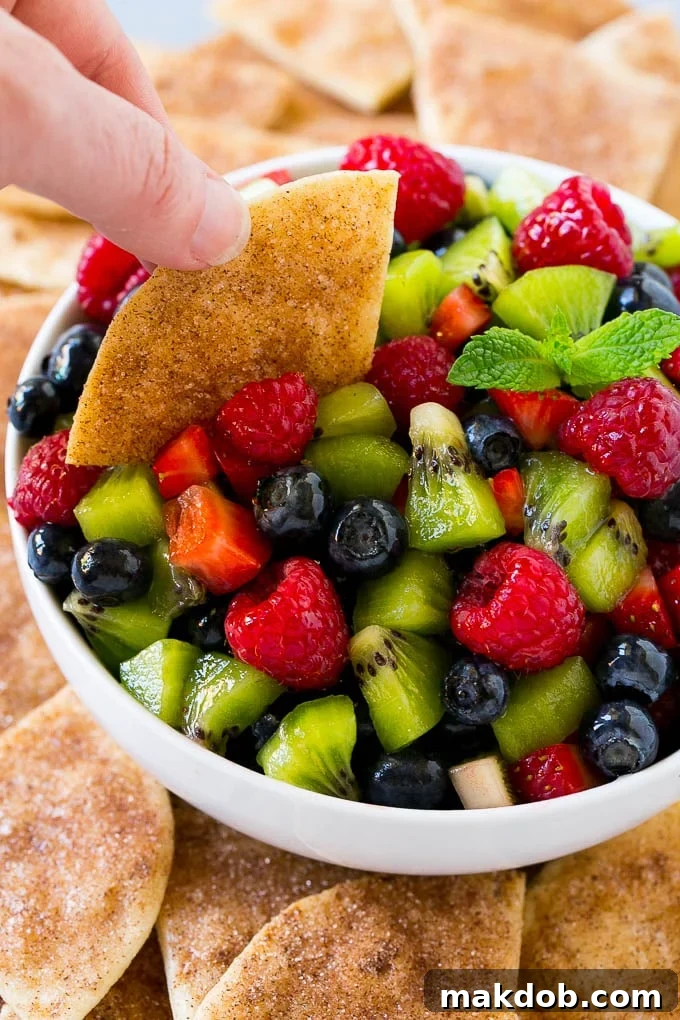 Fruit salsa with a cinnamon sugar chip scooping some out.