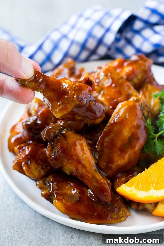 Fall-Off-The-Bone Slow Cooker Wings 5 A hand reaching for a crock pot wing coated in sauce.