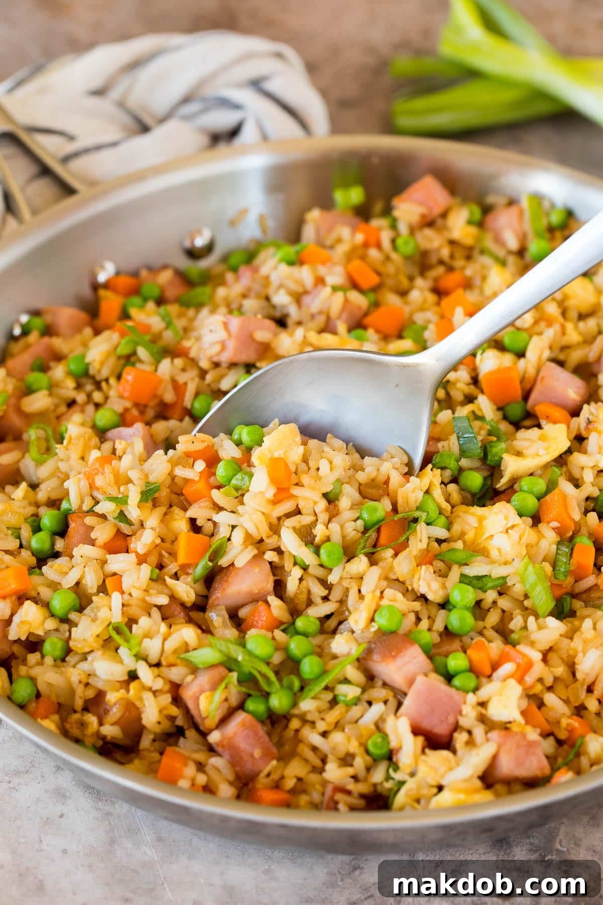 A pan of ham fried rice with a spoon in it.