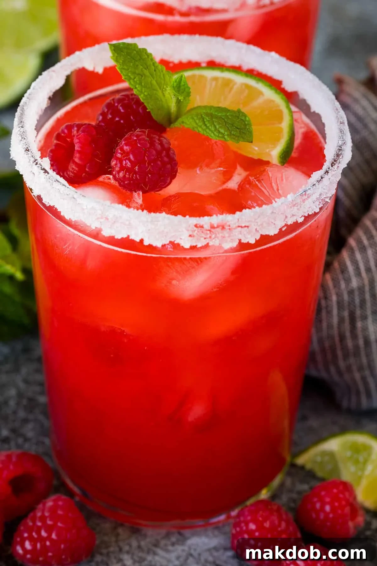 A raspberry margarita with a sugar rim and fresh berries on top.
