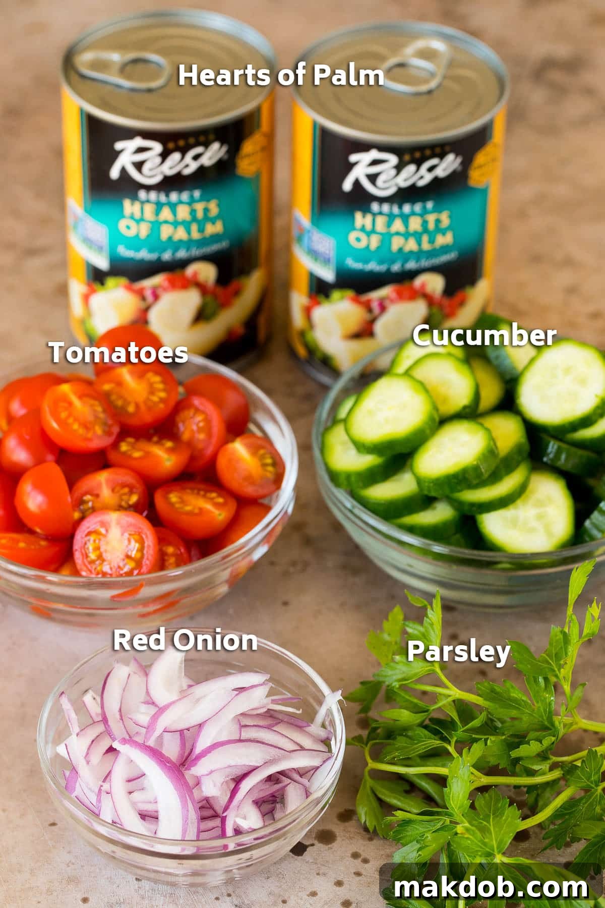 Cans of hearts of palm and bowls of sliced vegetables.
