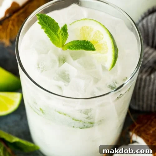A coconut mojito in a glass, garnished with fresh mint and a lime wedge.
