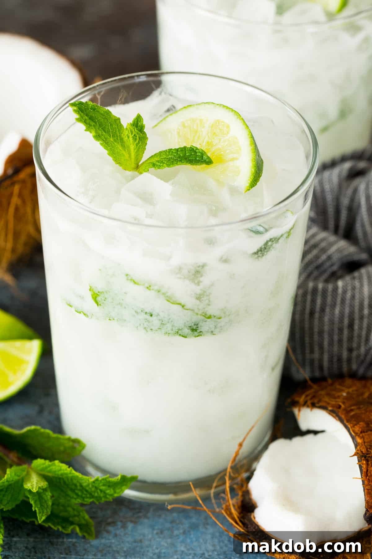A glass of coconut mojito cocktail topped with a lime slice and mint.